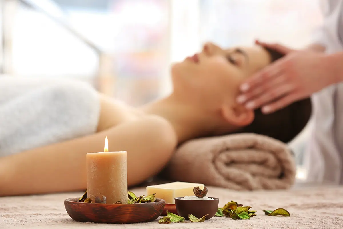 Aromatherapy candle and oils beside a relaxing wellness session